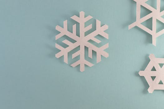 Elegant paper snowflakes on a pale blue background, perfect for winter or holiday decor.