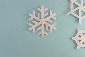 Elegant paper snowflakes on a pale blue background, perfect for winter or holiday decor.